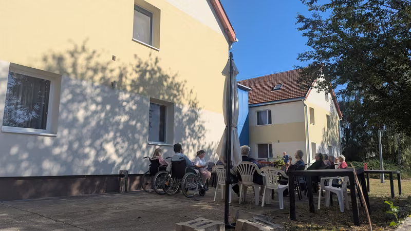Lakók és látogatók az épület melletti teraszon, a szabadban